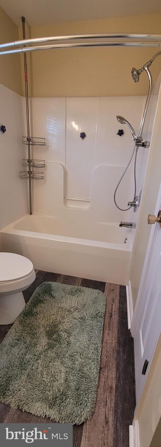 bathroom featuring  shower combination, wood finished floors, and toilet