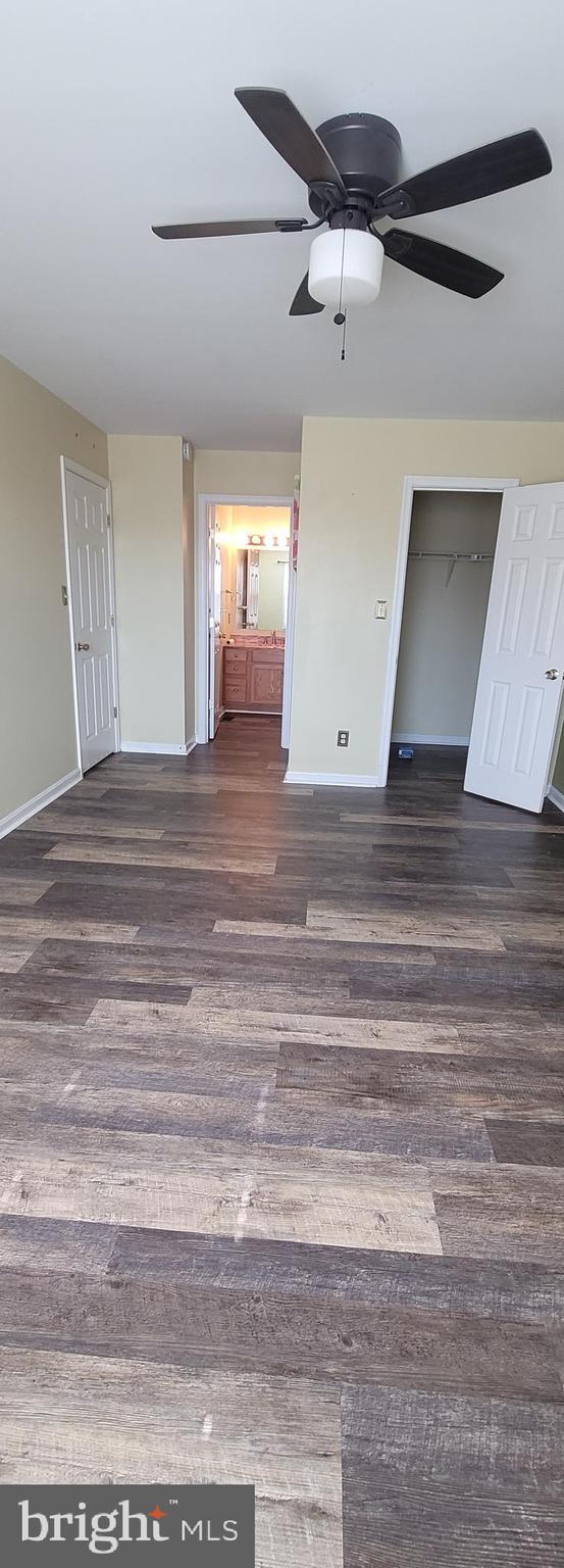 interior space featuring a ceiling fan, baseboards, and dark wood-style flooring