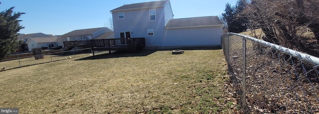 rear view of property featuring a yard, a wooden deck, and fence