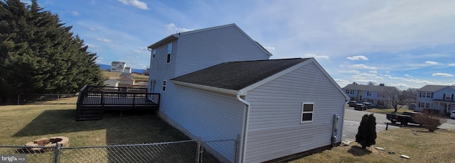 view of side of home with a yard, fence, and a wooden deck