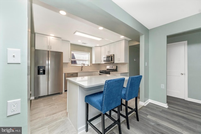 kitchen with tasteful backsplash, stainless steel appliances, kitchen peninsula, and white cabinets