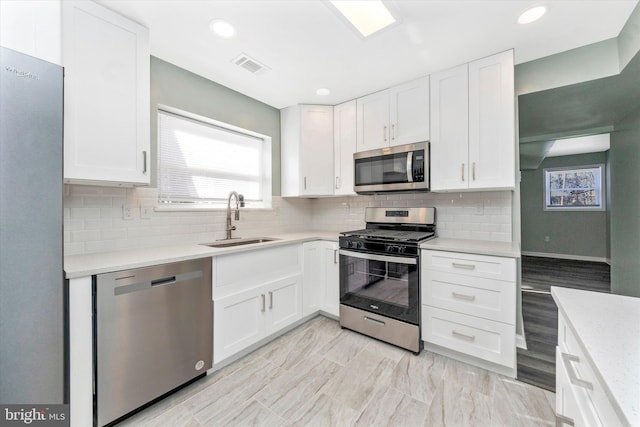 kitchen with white cabinetry, sink, decorative backsplash, and stainless steel appliances