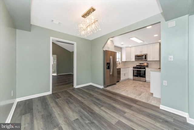 kitchen featuring a notable chandelier, light wood-type flooring, white cabinets, and appliances with stainless steel finishes