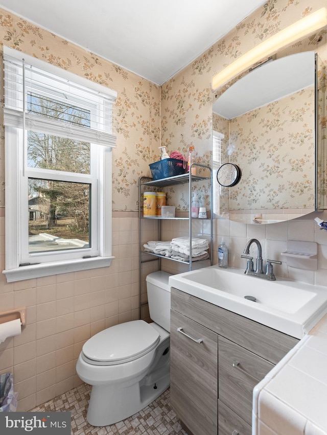 bathroom with toilet, washer / dryer, tile walls, vanity, and tile patterned flooring