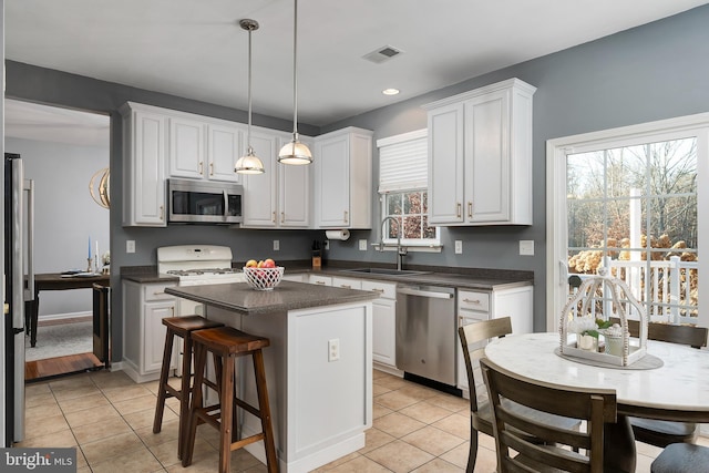 kitchen with sink, hanging light fixtures, stainless steel appliances, a center island, and white cabinets