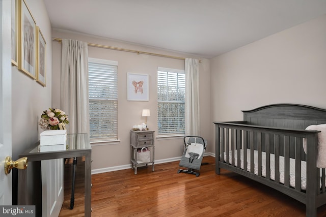 bedroom with hardwood / wood-style flooring and a nursery area