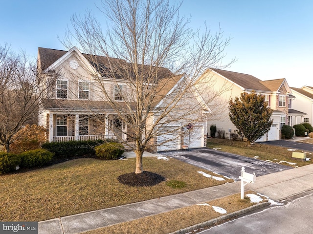 view of property featuring a garage, a front yard, and covered porch