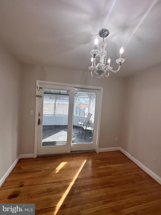 unfurnished dining area with hardwood / wood-style flooring and a chandelier