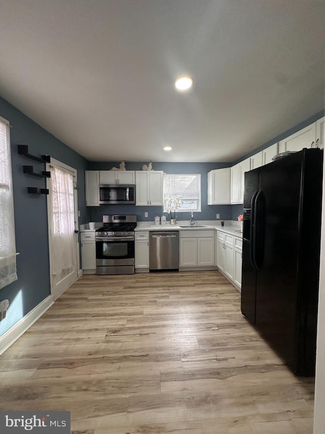 kitchen with white cabinetry, sink, stainless steel appliances, and light wood-type flooring