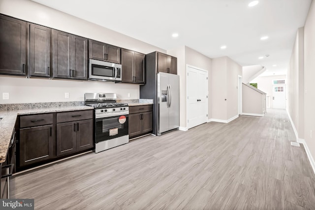 kitchen featuring dark brown cabinetry, appliances with stainless steel finishes, light stone countertops, and light hardwood / wood-style flooring