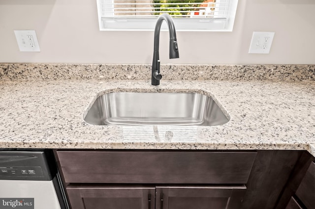 details with dark brown cabinetry, sink, stainless steel dishwasher, and light stone countertops