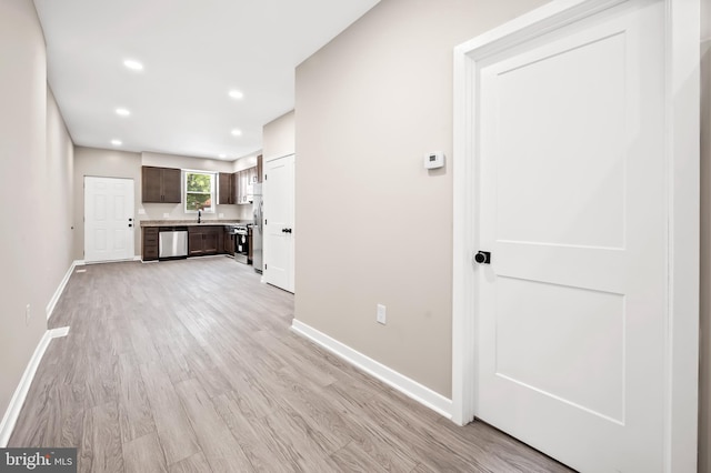 unfurnished living room featuring sink and light hardwood / wood-style floors