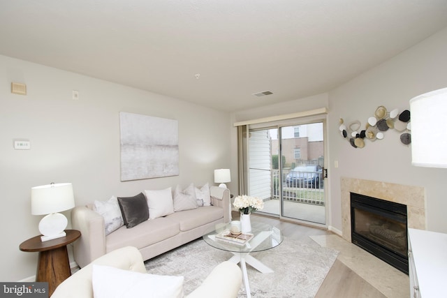 living room featuring a tiled fireplace and light wood-type flooring