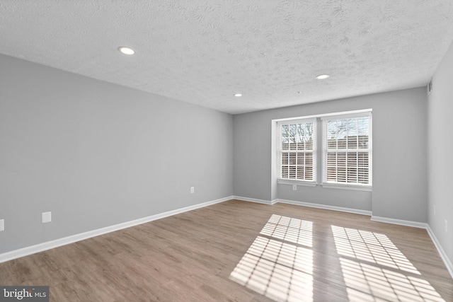 empty room with a textured ceiling and light wood-type flooring