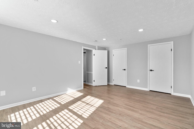 interior space featuring two closets, light hardwood / wood-style flooring, and a textured ceiling