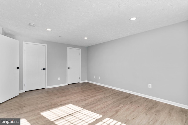 empty room with light hardwood / wood-style floors and a textured ceiling