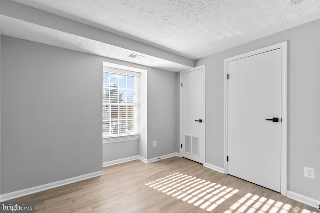 empty room featuring a textured ceiling and light wood-type flooring