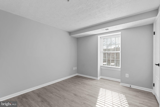 empty room featuring a textured ceiling and light hardwood / wood-style flooring