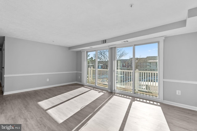 empty room featuring wood-type flooring and a textured ceiling