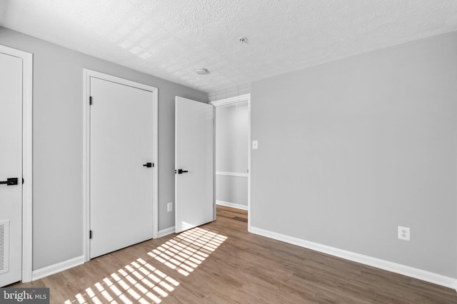 unfurnished bedroom featuring hardwood / wood-style floors and a textured ceiling