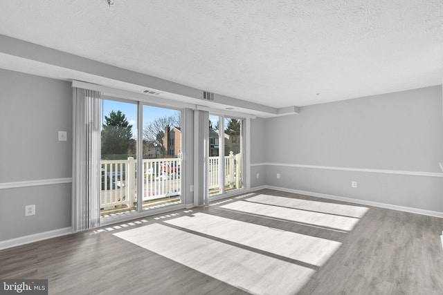 unfurnished room featuring hardwood / wood-style flooring and a textured ceiling