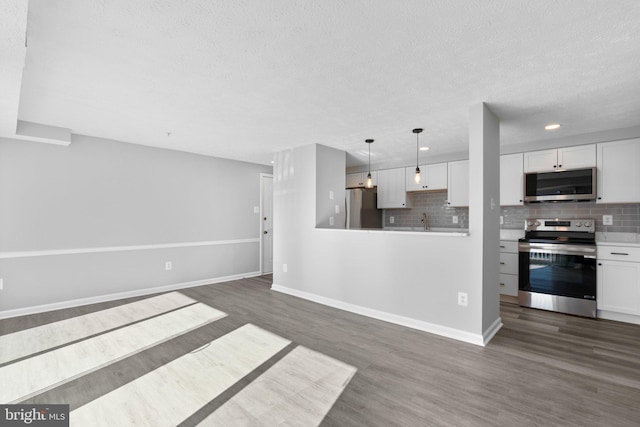 kitchen featuring pendant lighting, dark hardwood / wood-style flooring, white cabinets, and appliances with stainless steel finishes