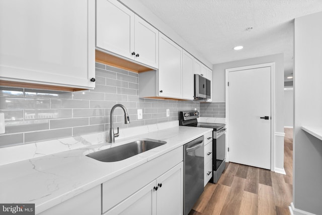 kitchen featuring appliances with stainless steel finishes, sink, white cabinets, and light stone counters