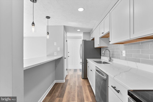 kitchen with sink, hanging light fixtures, light stone countertops, white cabinets, and stainless steel dishwasher