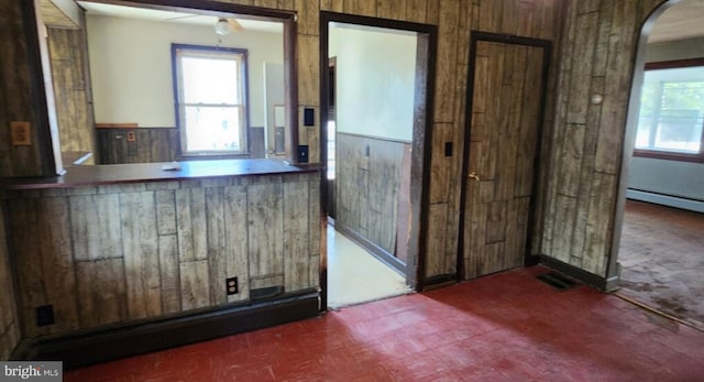 kitchen with a baseboard radiator, a wealth of natural light, and wood walls