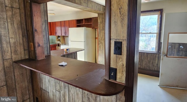 kitchen with plenty of natural light, kitchen peninsula, and white fridge