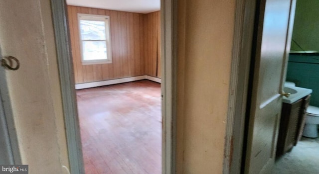 hallway with wood walls and a baseboard heating unit