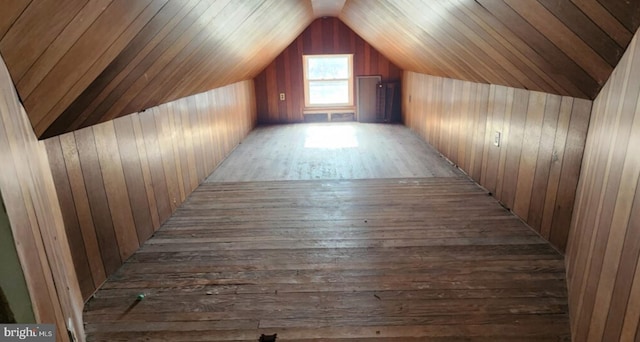 bonus room featuring dark wood-type flooring, wooden walls, and vaulted ceiling