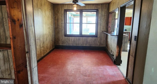 empty room featuring ceiling fan and wooden walls