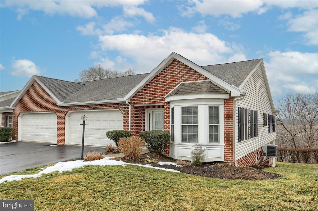 view of front of home with cooling unit, a garage, and a front lawn