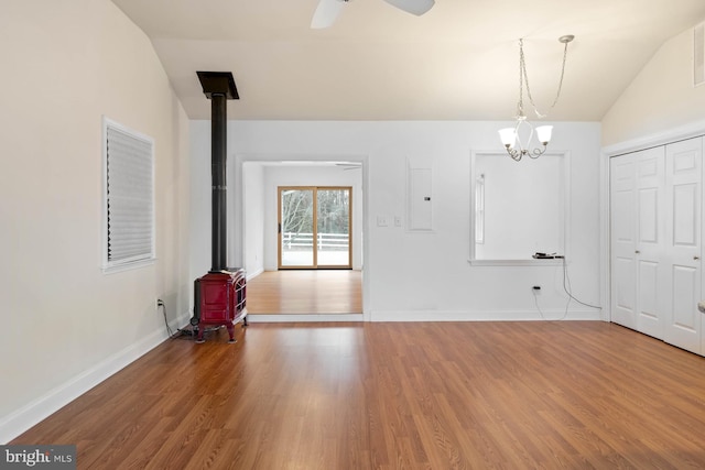 interior space with vaulted ceiling, wood finished floors, a wood stove, and baseboards