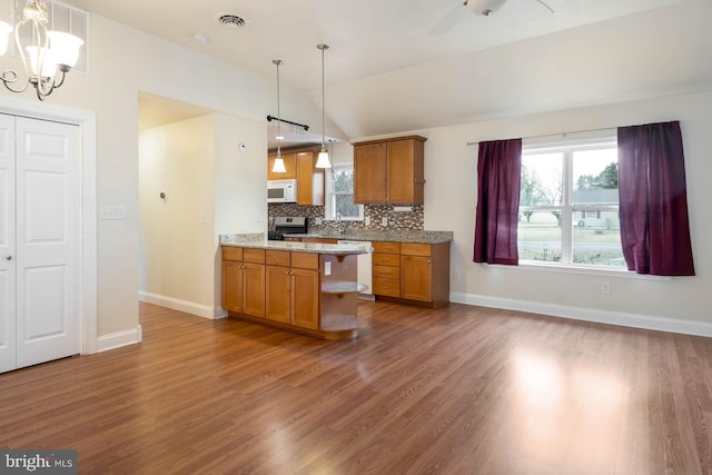 kitchen featuring brown cabinets, visible vents, decorative backsplash, white microwave, and stainless steel range with gas stovetop