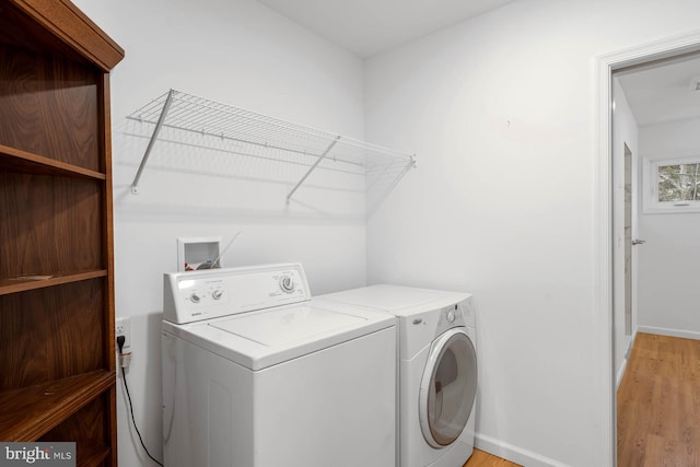 laundry room with laundry area, baseboards, light wood finished floors, and washing machine and clothes dryer