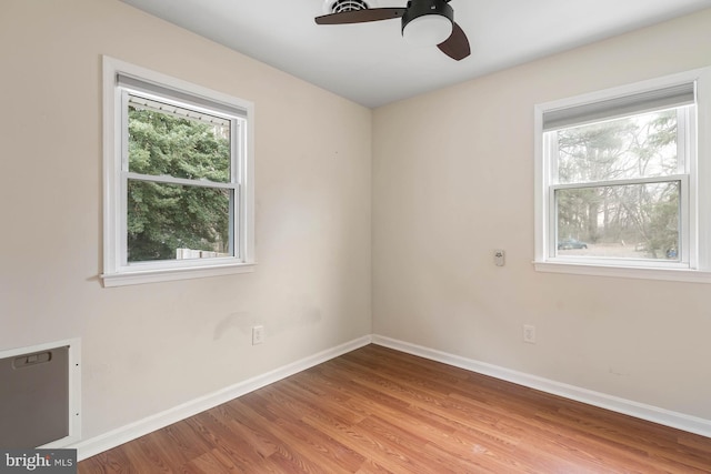 empty room with a wealth of natural light, baseboards, and wood finished floors