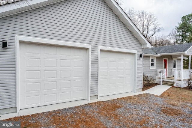 garage with dirt driveway and a porch