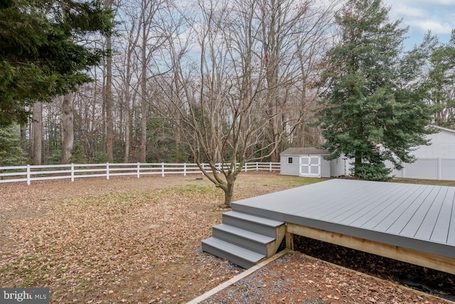 view of yard with a fenced backyard, a shed, a deck, and an outbuilding