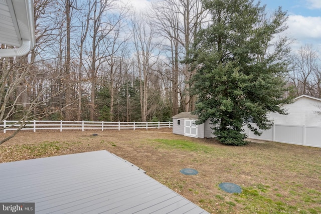 wooden deck with an outbuilding, a shed, a lawn, and a fenced backyard