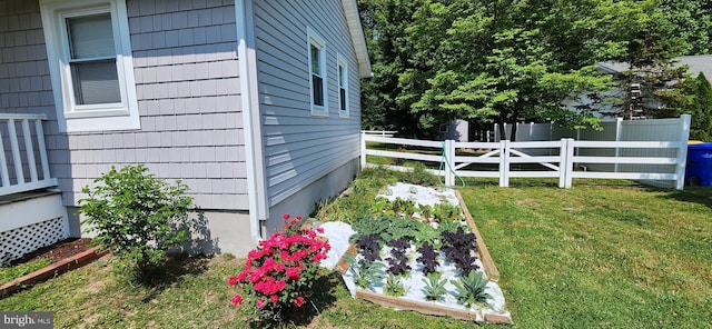 view of property exterior featuring a yard, fence, and a garden