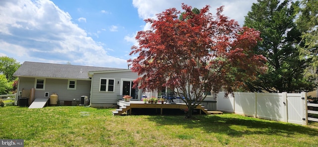 rear view of property featuring a fenced backyard, central AC unit, a deck, and a lawn