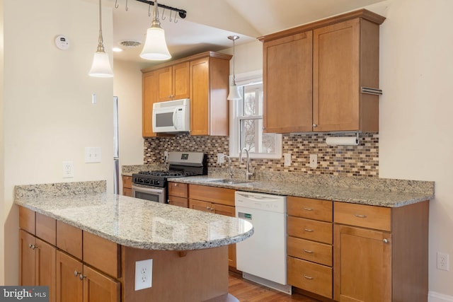 kitchen with decorative backsplash, a sink, light stone countertops, white appliances, and a peninsula