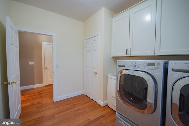 laundry area with light wood-type flooring, cabinet space, baseboards, and washing machine and clothes dryer