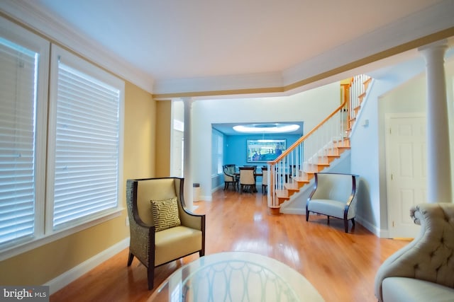 living area featuring ornamental molding, stairway, wood finished floors, and ornate columns