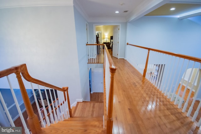 hallway featuring baseboards, wood finished floors, crown molding, an upstairs landing, and recessed lighting