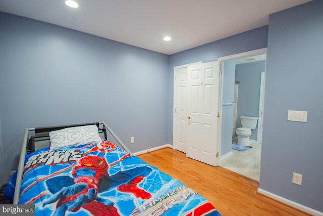 bedroom with recessed lighting, connected bathroom, baseboards, and wood finished floors