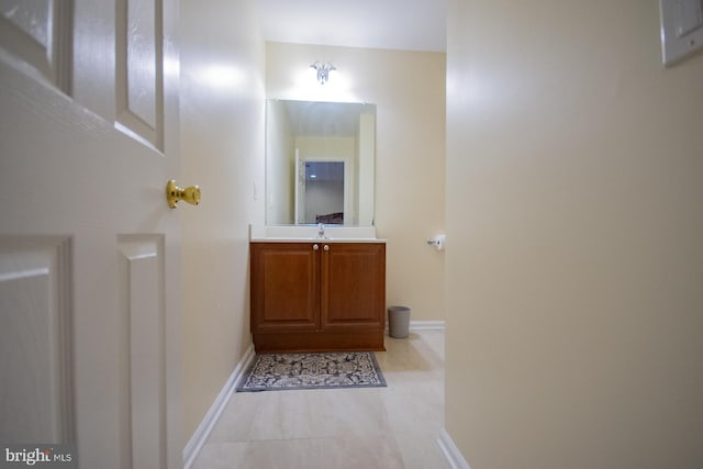 half bathroom featuring tile patterned floors, baseboards, and vanity