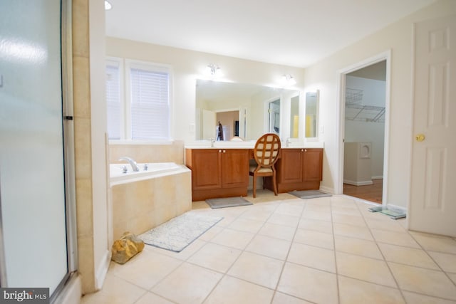 bathroom with a garden tub, a shower with shower door, vanity, a spacious closet, and tile patterned floors